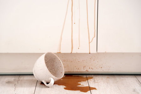 Overturned cup and spilled coffee on floor in kitchenの写真素材