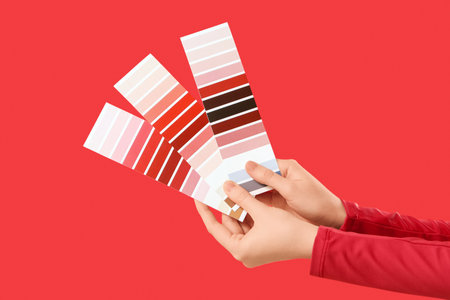 Female hands with color palettes on red backgroundの写真素材