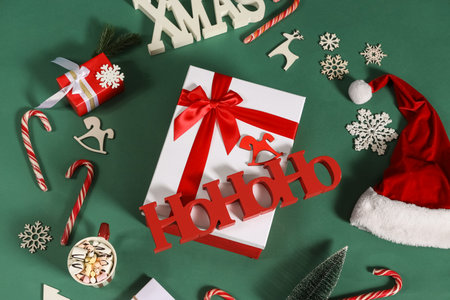 Beautiful gift boxes with candy canes, Christmas decorations, cup of cocoa and word HOHOHO on green background, top viewの写真素材