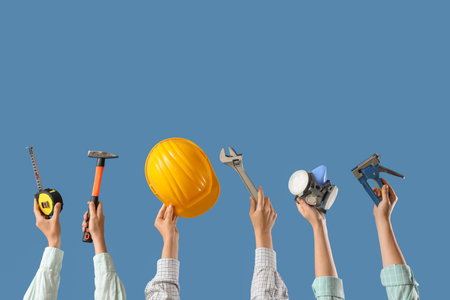 Hands with hardhat and construction tools on blue backgroundの写真素材