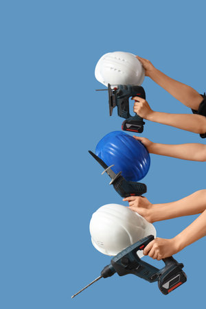 Hands with hardhats and construction tools on blue backgroundの写真素材