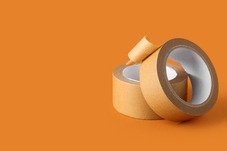 Rolls of brown masking tape on orange backgroundの写真素材
