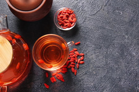 Glass cup and teapot of hot goji tea on dark backgroundの写真素材