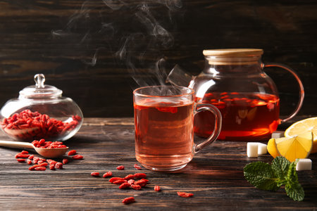 Glass cup of hot goji tea with mint and lemon on wooden backgroundの写真素材