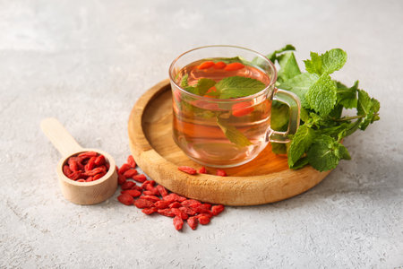 Glass cup of hot goji tea with mint and berries on gray backgroundの写真素材