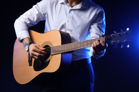 Young man playing guitar on black backgroundの写真素材