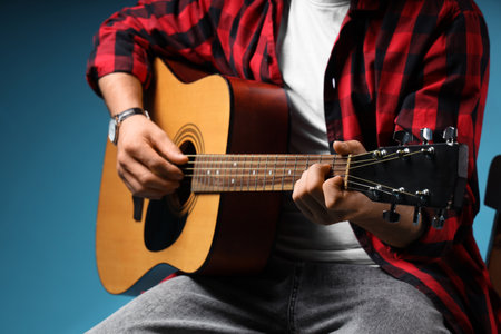 Young man playing guitar on blue backgroundの写真素材