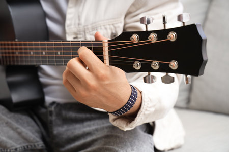 Young man playing acoustic guitar at homeの写真素材