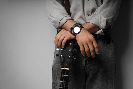 Young man with guitar on gray backgroundの写真素材