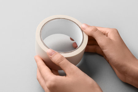 Female hands with roll of white masking tape on gray backgroundの写真素材