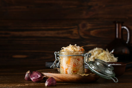 Jar with tasty sauerkraut and garlic on wooden backgroundの写真素材