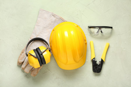 Hardhat with protective earmuffs and safety equipment on green grunge backgroundの写真素材