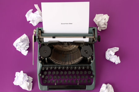 Vintage typewriter, paper sheet with text CHAPTER ONE and crumpled paper on purple background, closeupの写真素材