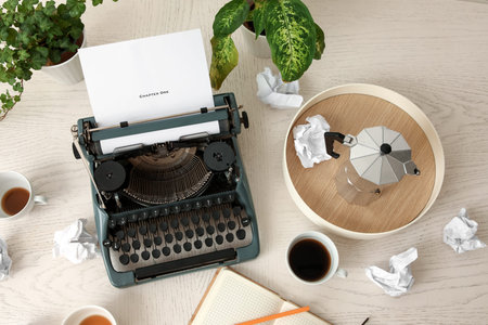 Vintage typewriter, cups of coffee, houseplants and crumpled paper on white wooden background,...