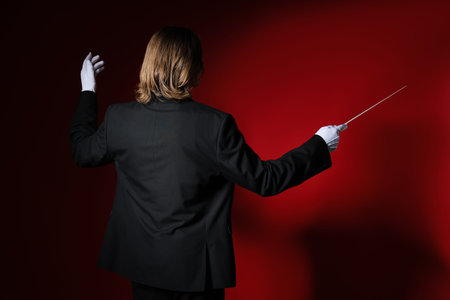 Male conductor on red background, back view