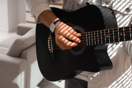 Young man playing acoustic guitar at homeの写真素材