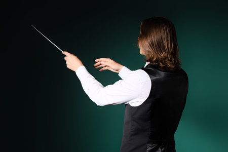 Male conductor on dark green background, back view