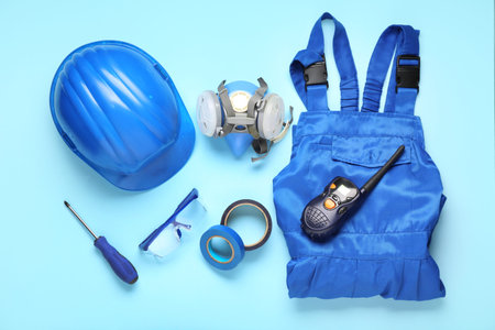 Hardhat, uniform and safety equipment on blue background