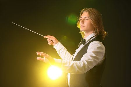 Young male conductor on dark background