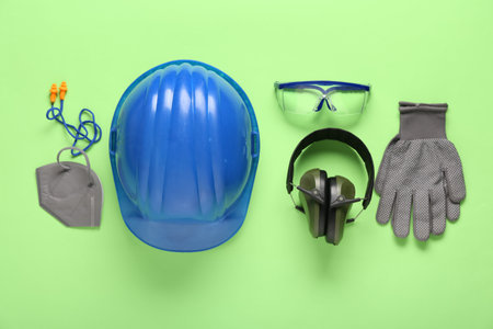 Hardhat and safety equipment on green backgroundの写真素材
