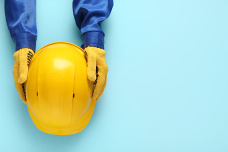 Worker holding hardhat on blue backgroundの写真素材