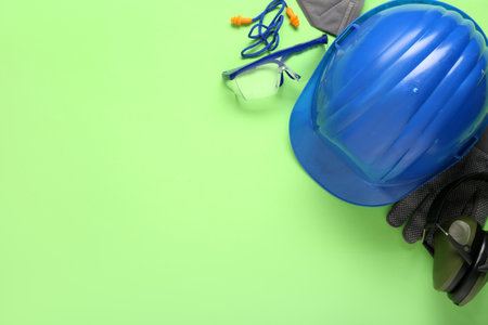 Hardhat and safety equipment on green backgroundの写真素材