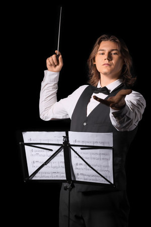Male conductor with note sheets on black background