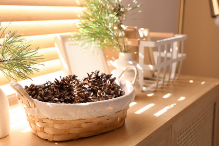 Basket with coniferous cones on commode near windowの写真素材