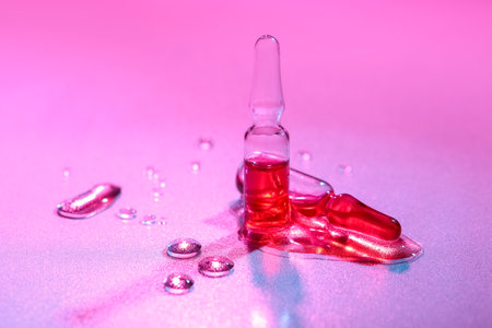 Glass ampoules with water drops on pink backgroundの写真素材