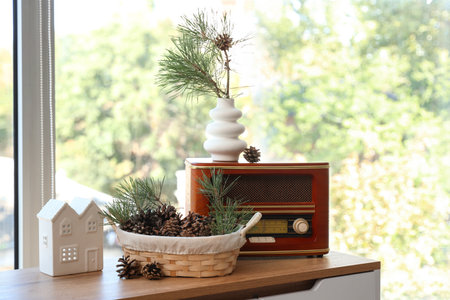 Basket with coniferous cones and retro radio on commode near windowの写真素材
