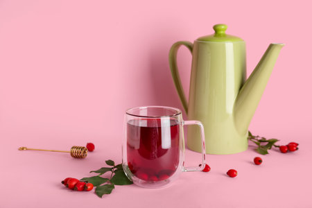 Glass cup of hot rose hip tea and berries on pink backgroundの写真素材