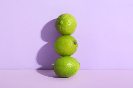 Fresh ripe limes on lilac backgroundの写真素材