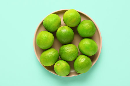 Plate with fresh ripe limes on turquoise backgroundの写真素材