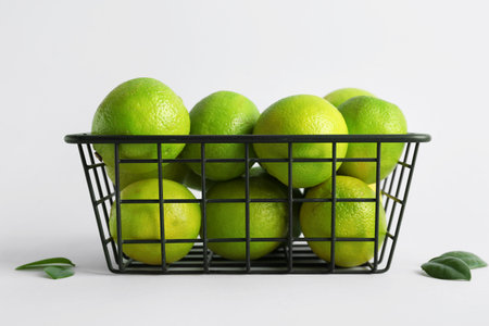 Basket with fresh ripe limes on gray backgroundの写真素材