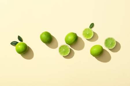 Fresh ripe limes and leaves on yellow backgroundの写真素材