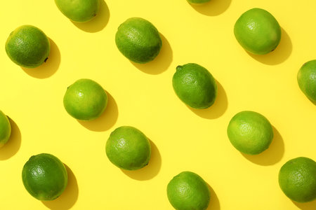 Many fresh ripe limes on yellow background