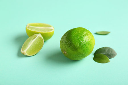Fresh ripe limes and leaves on turquoise backgroundの写真素材