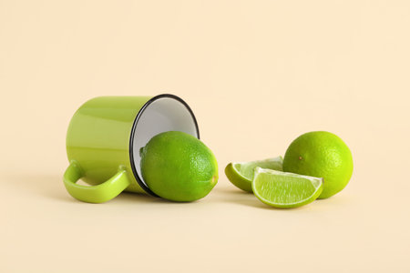 Cup with fresh ripe limes on beige backgroundの写真素材