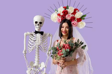 Beautiful young happy woman dressed as dead bride for Halloween with skeleton and bouquet of flowers on purple backgroundの写真素材