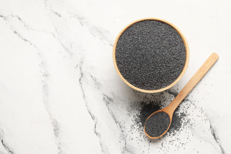 Bowl and wooden spoon with poppy seeds on white backgroundの写真素材