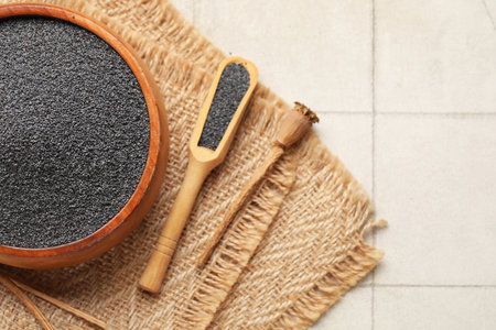 Wooden bowl and scoop with poppy seeds on white tile backgroundの写真素材