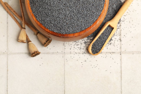 Wooden bowl and scoop with poppy seeds on white tile backgroundの写真素材