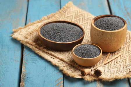 Bowls with poppy seeds on blue wooden background, closeupの写真素材