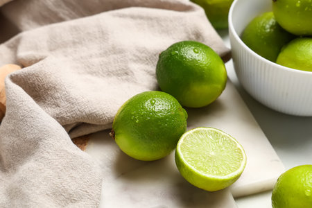 Cutting board with fresh ripe limes on white background, closeup