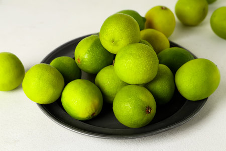 Plate with fresh ripe limes on white background, closeupの写真素材