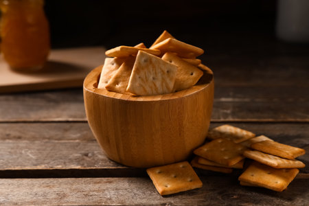 Composition with bowl of tasty crackers on brown wooden table, closeupの写真素材