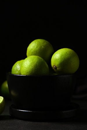 Bowl with fresh ripe limes on black backgroundの写真素材