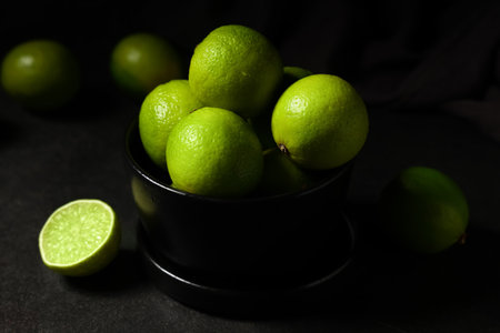 Bowl with fresh ripe limes on black background, closeupの写真素材