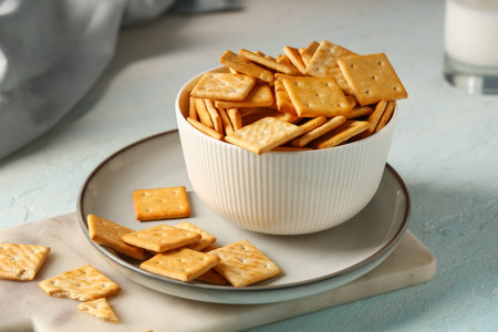 Composition with bowl of tasty crackers on blue background, closeupの写真素材