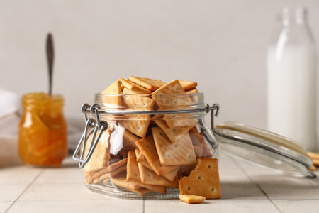 Composition with glass jar of tasty crackers on beige tile background, closeupの写真素材